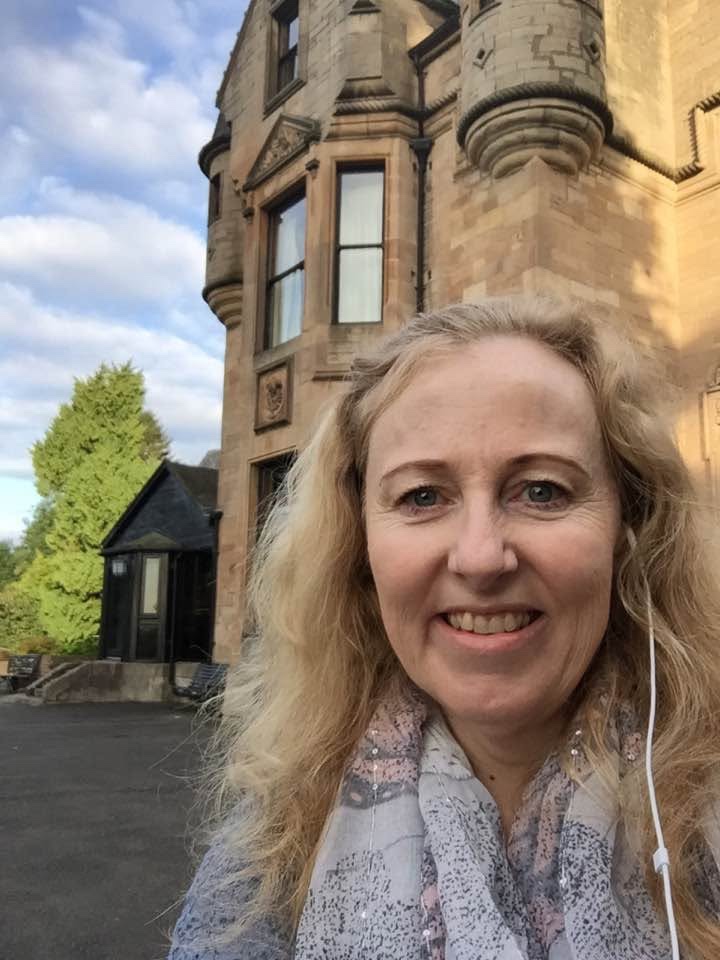 Lyn outside a Scottish castle, looking toward the reader